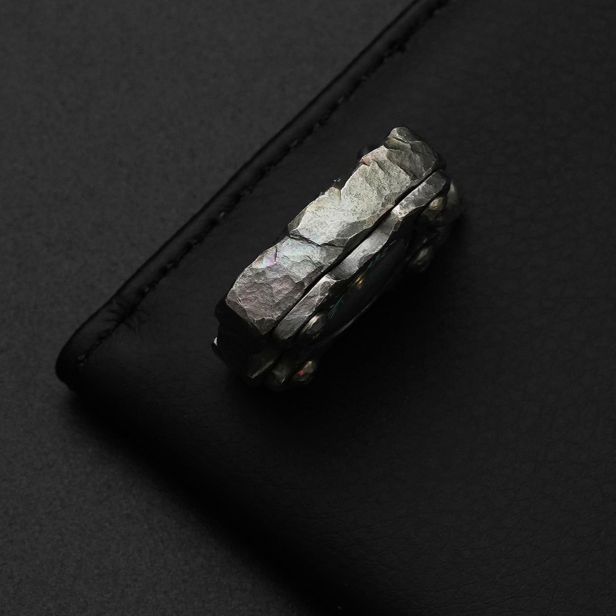 Edge detail of the MecArmy CMP2-HC hand-carved titanium EDC compass with irregular sculpted rock-like facets